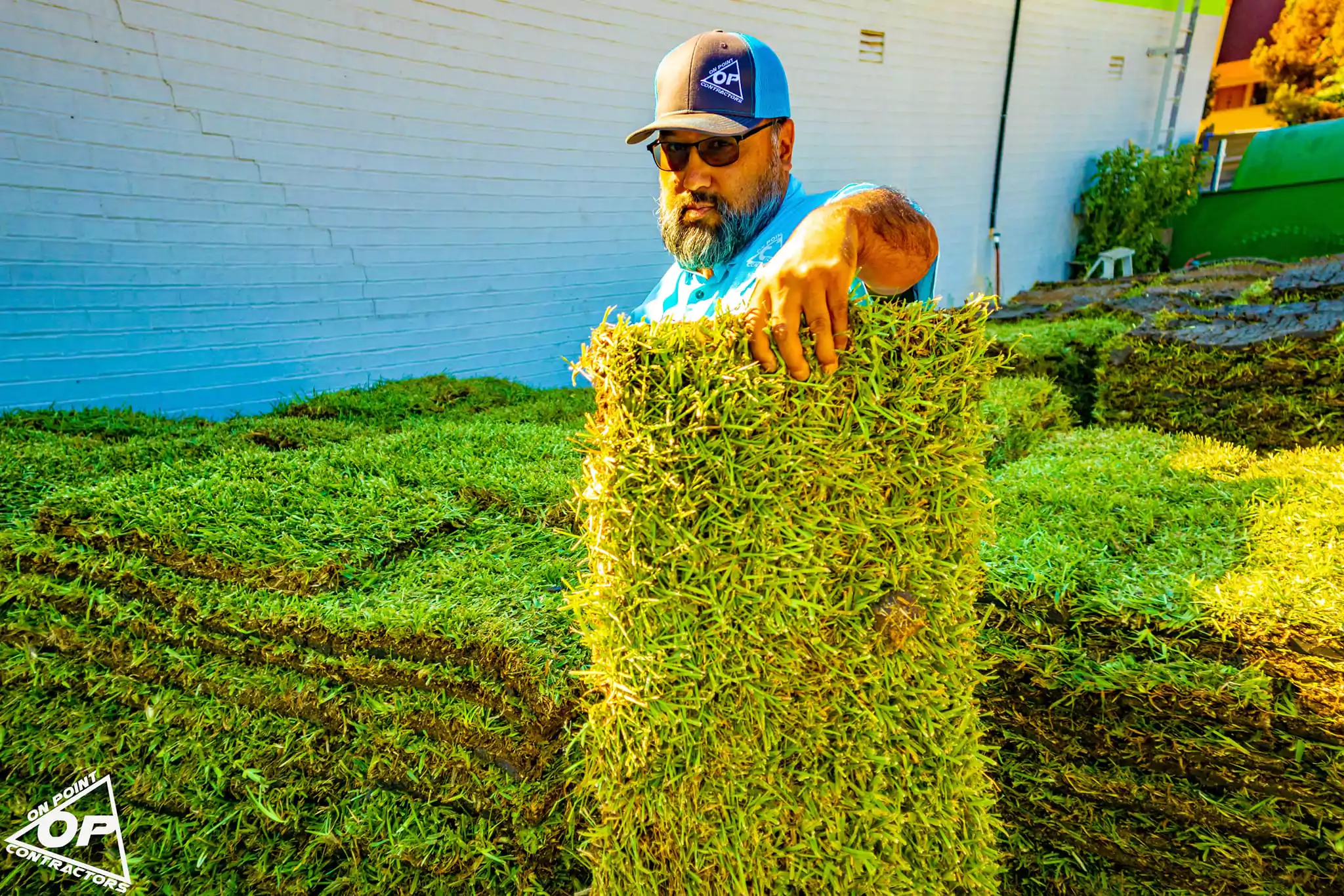 Man holding a fresh roll of St. Augustine Raleigh sod at a sod installation site